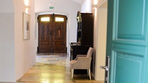 Un pasillo con una puerta de madera al final, una silla y un armario.
