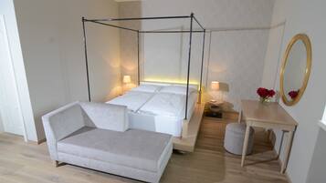 Une chambre à coucher moderne avec un lit à baldaquin, une table de chevet avec une lampe, une petite table ronde ornée d’un vase de fleurs et un grand miroir accroché au mur.