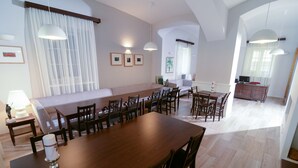Un comedor espacioso con una larga mesa de madera y varias sillas, un sofá y un mueble bajo.