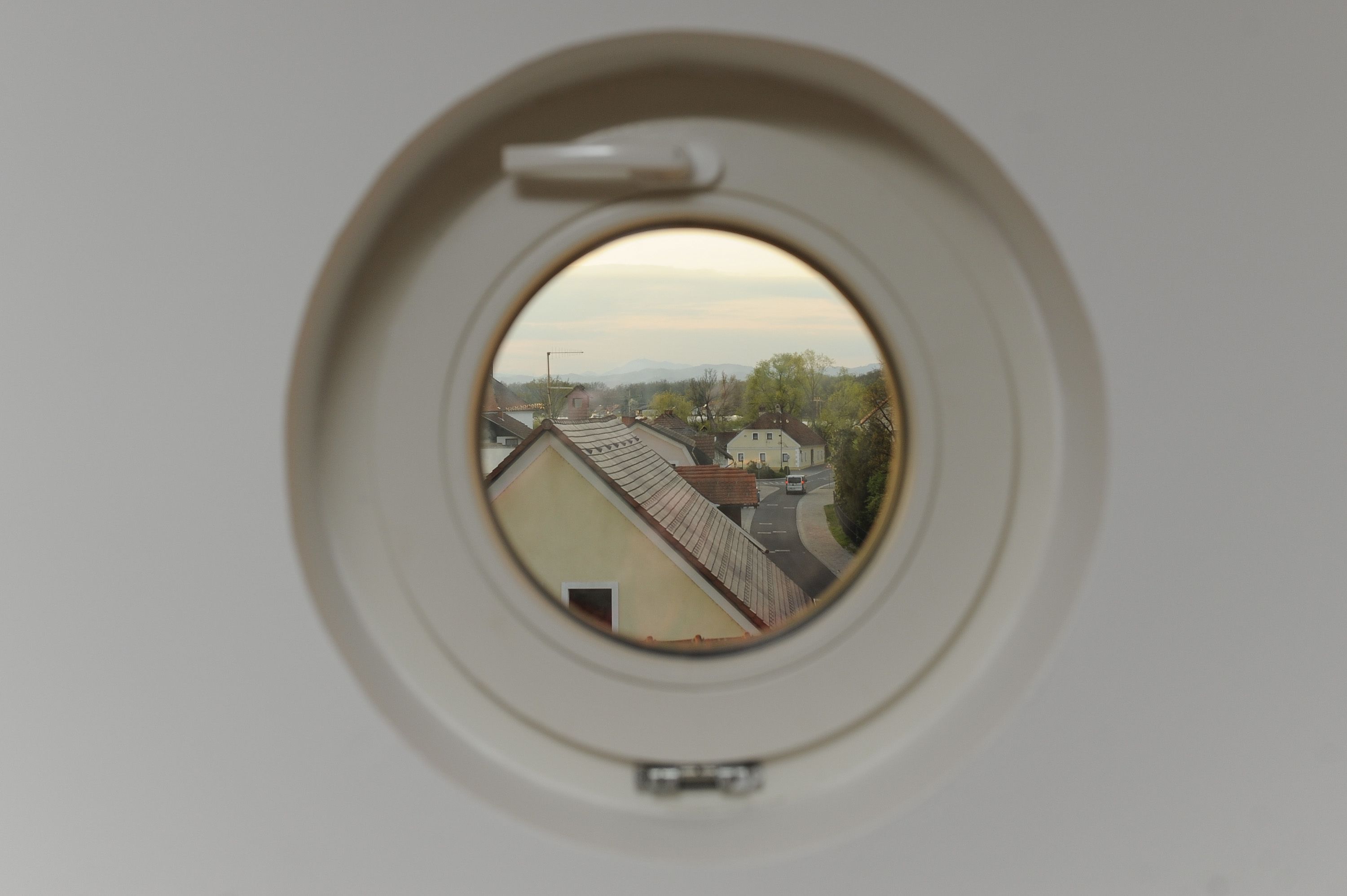 Una ventana redonda con vistas a una calle y edificios.