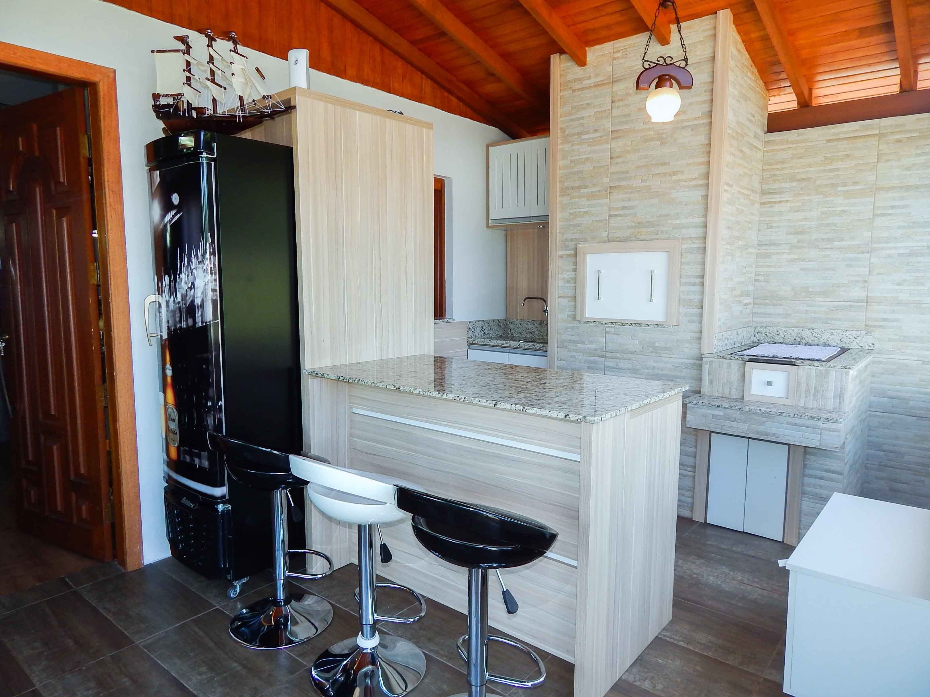 A modern kitchen with a central island, bar stools, and a ship model on the refrigerator.