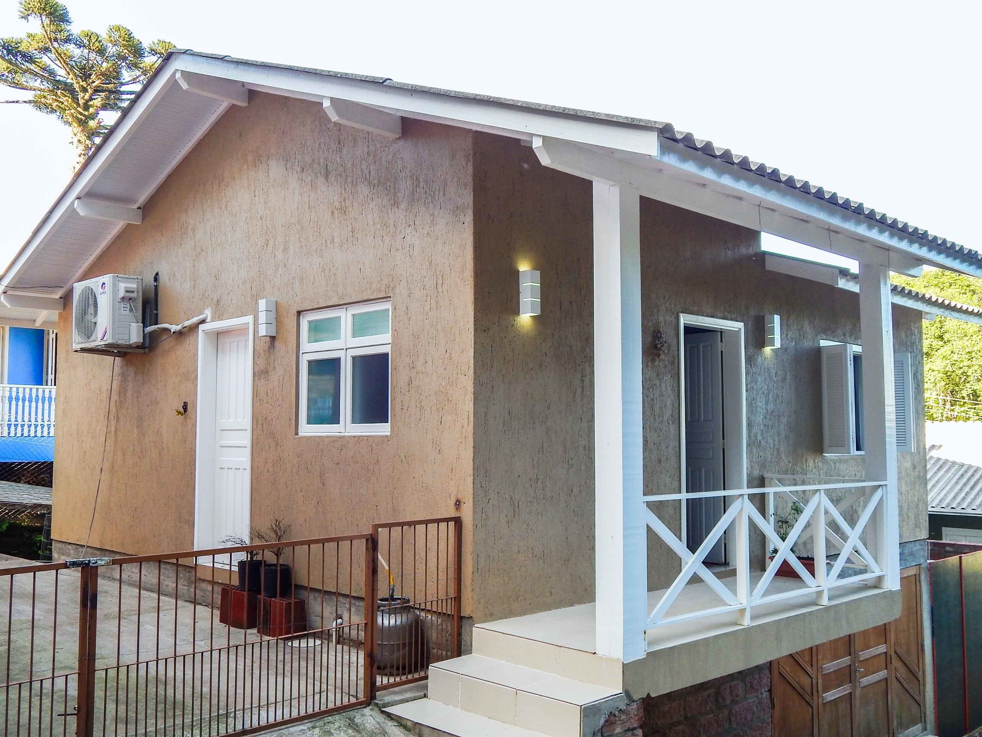 A single-story house with a porch, a white door, and a small window.