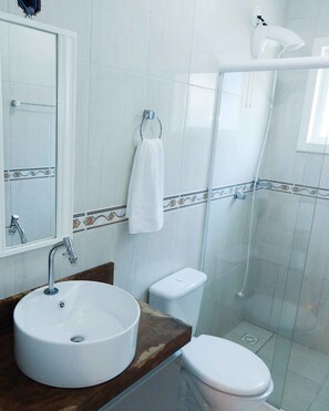 A bathroom with a white sink, toilet, and shower.