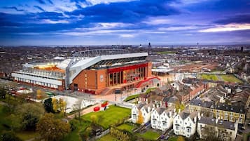 A stadium with a modern design, surrounded by residential buildings and a parking area.
