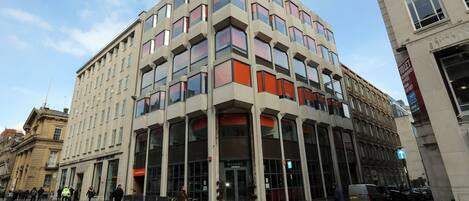 A multi-story building with a modern architectural design, featuring large windows and a ground-level entrance.