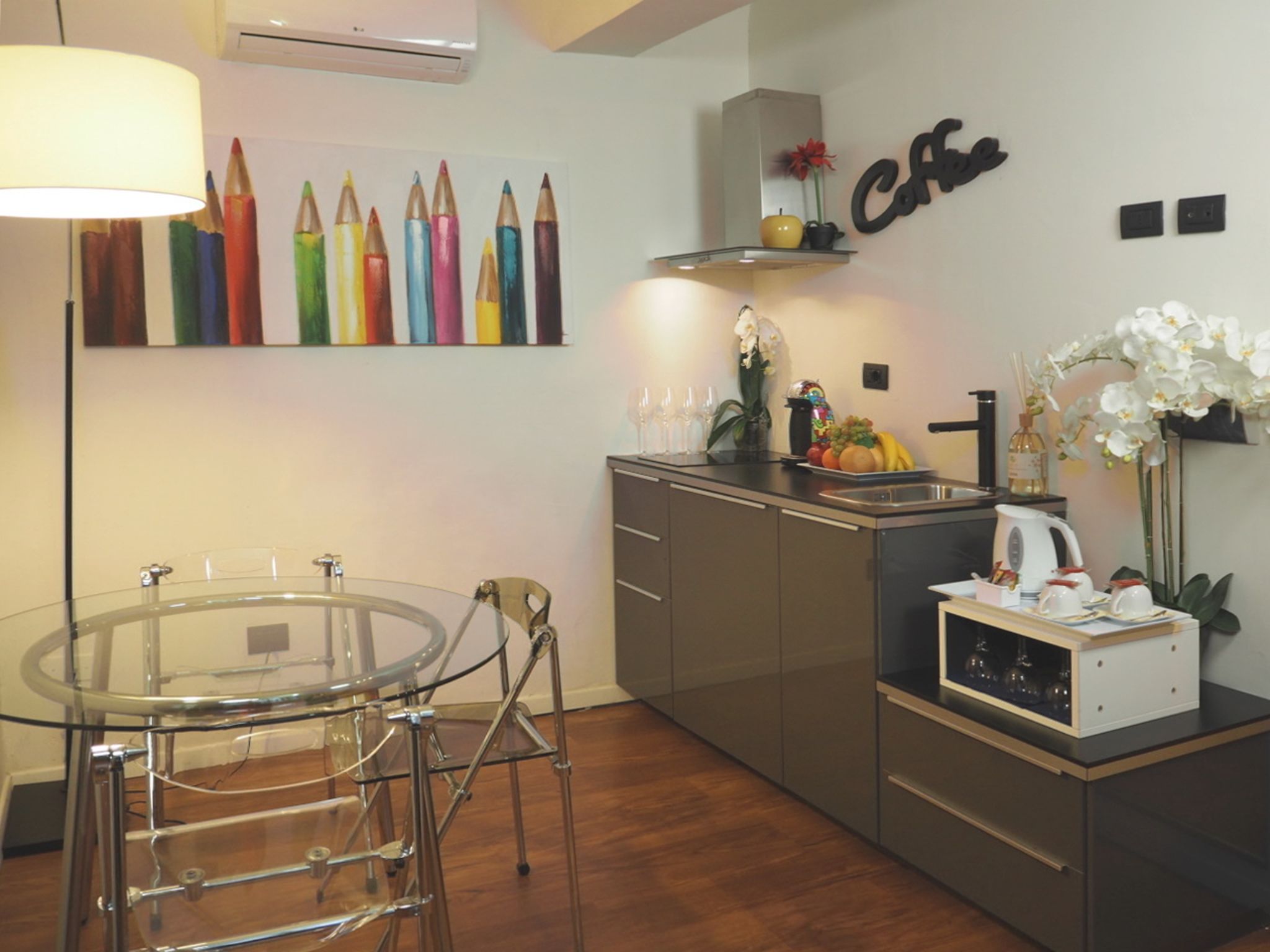 Una cucina moderna con un tavolo da pranzo in vetro, elettrodomestici in acciaio inossidabile e un'opera d'arte decorativa a parete.