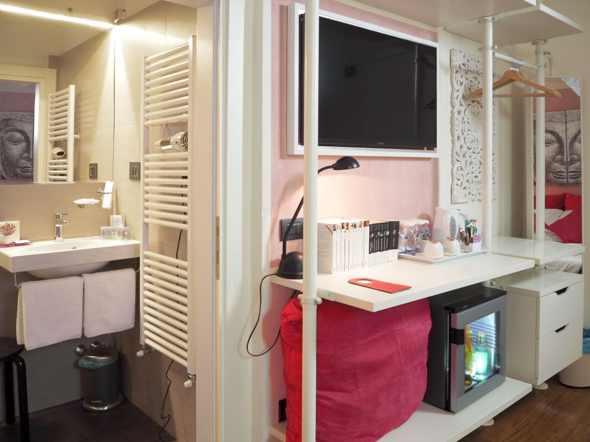 A modern bathroom with a vanity, towel rack, radiator, and a small refrigerator.