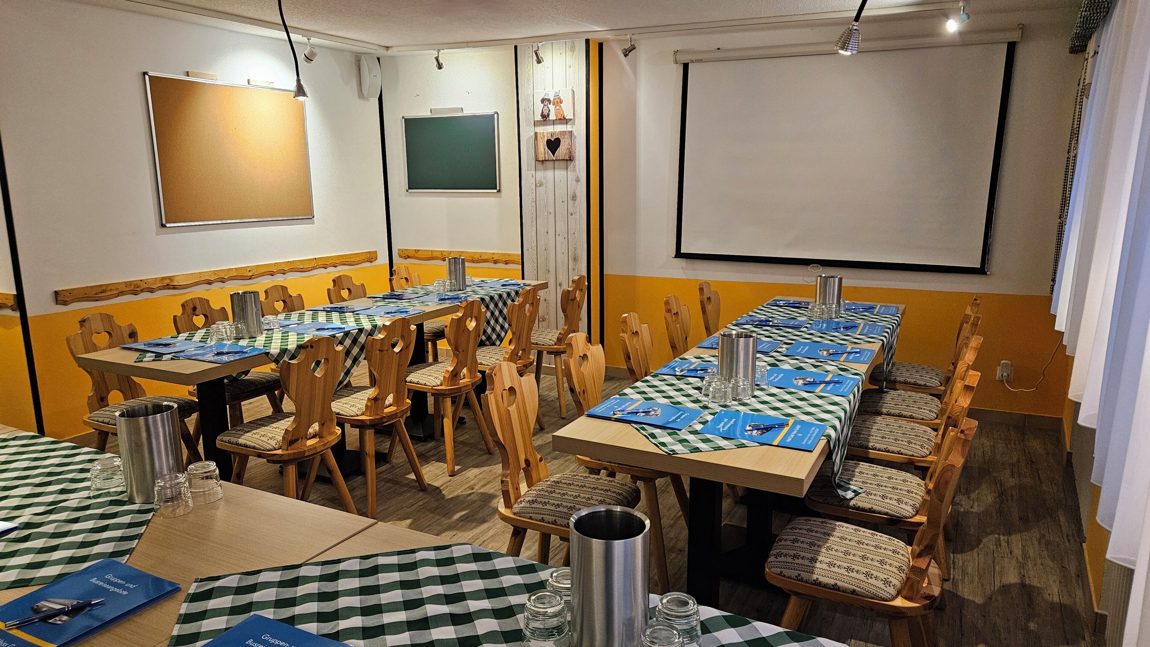 Ein Konferenzraum mit langem Tisch, Stühlen und einer Projektionsleinwand.