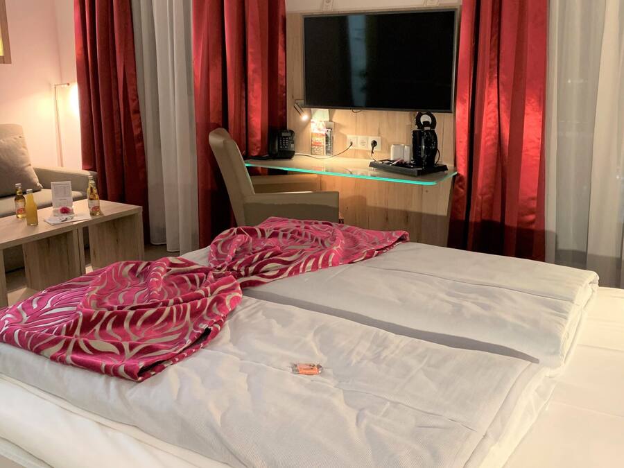 A hotel room with a bed, a desk with a computer, a TV, and a sofa.