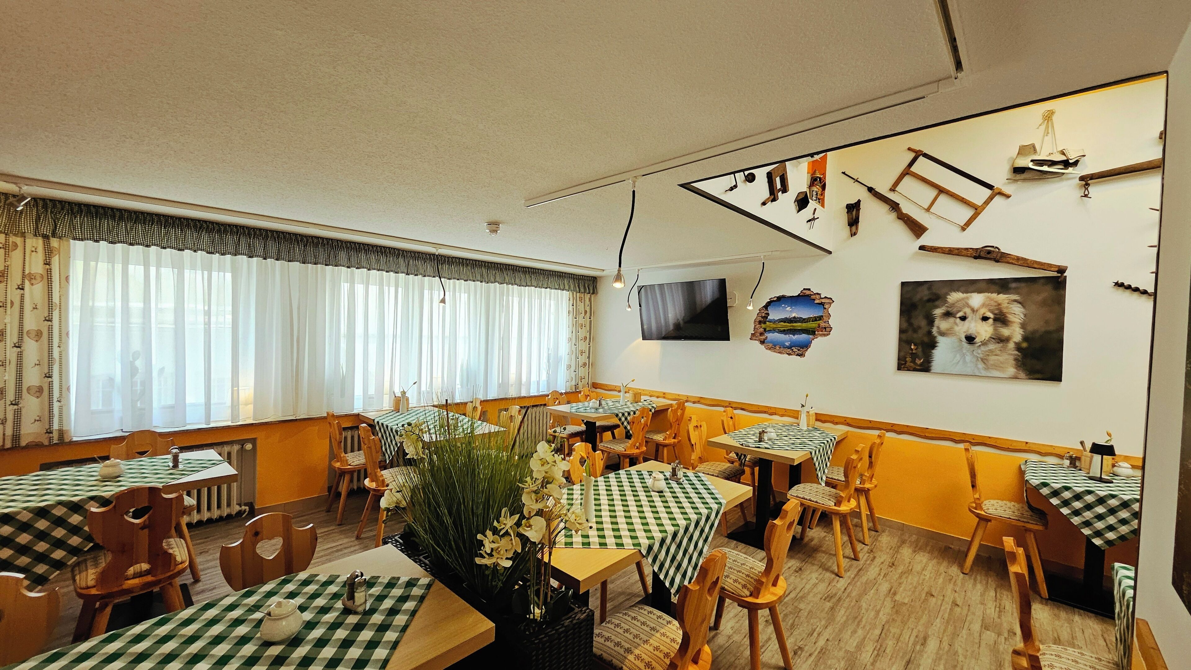 Comedor con manteles a cuadros, sillas de madera y un arreglo floral central.
