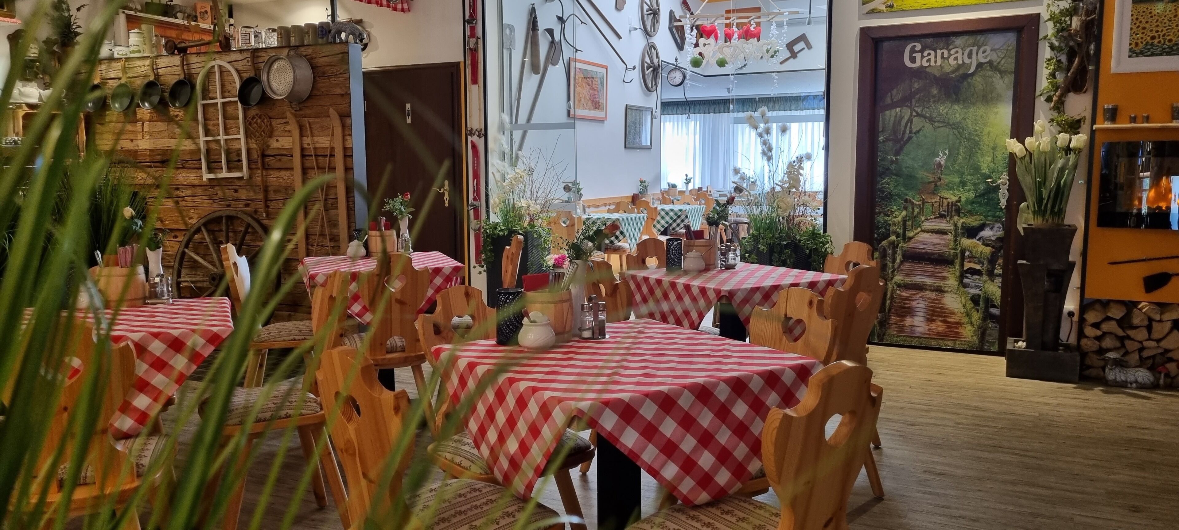 Un restaurante con mesas y sillas de madera, manteles a cuadros y una decoración rústica.