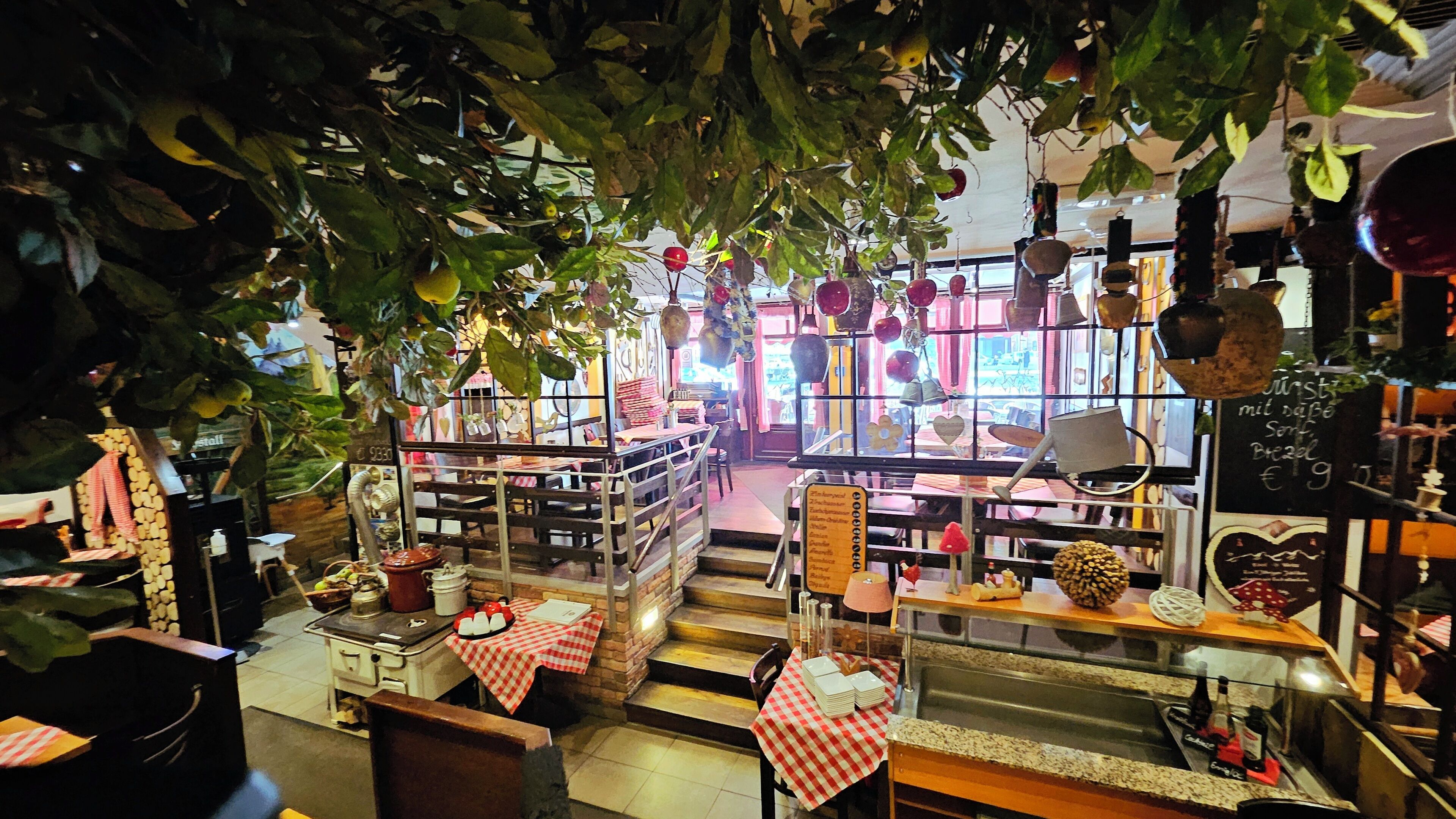 Un restaurante interior con mesas y sillas, una barra con alimentos y adornos colgantes.