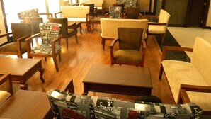 A hotel lobby with wooden flooring, multiple seating areas, and a television mounted on the wall. - Vesta Fuar Hotel (Izmir)