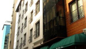 A multi-story building with balconies, a reflective glass facade, and green awnings. - Vesta Fuar Hotel (Izmir)