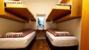 Een kleine kamer met twee stapelbedden, houten vloeren en een raam met uitzicht.