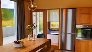 Een moderne keuken met een houten tafel, een roestvrijstalen koelkast en uitzicht op de omgeving.