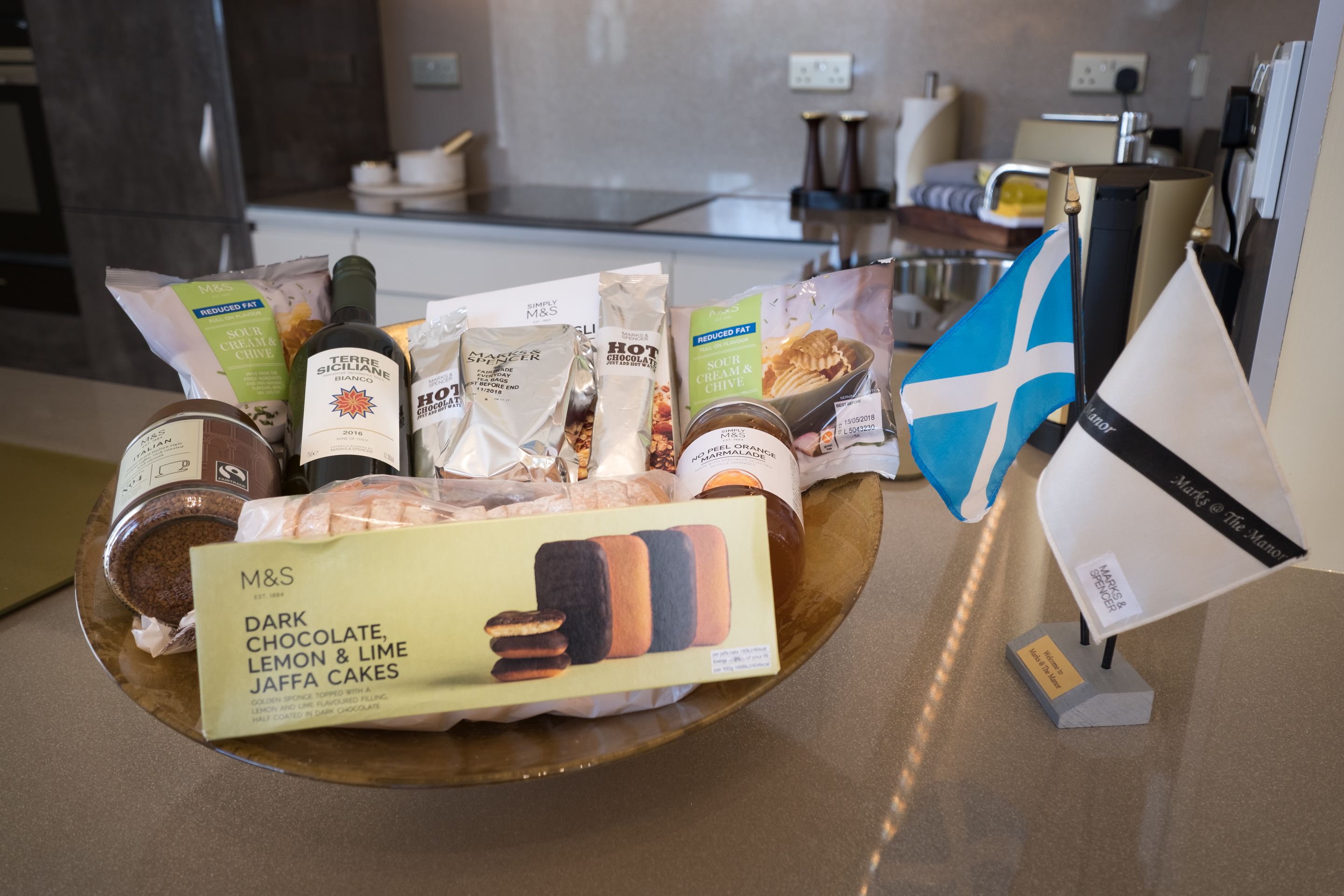 A display of M&S dark chocolate, lemon & lime Jaffa cakes, hot chocolate mix, and other snacks on a tray.