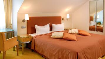 Una habitación de hotel con cama, mesita de noche, lámpara, silla y espejo.