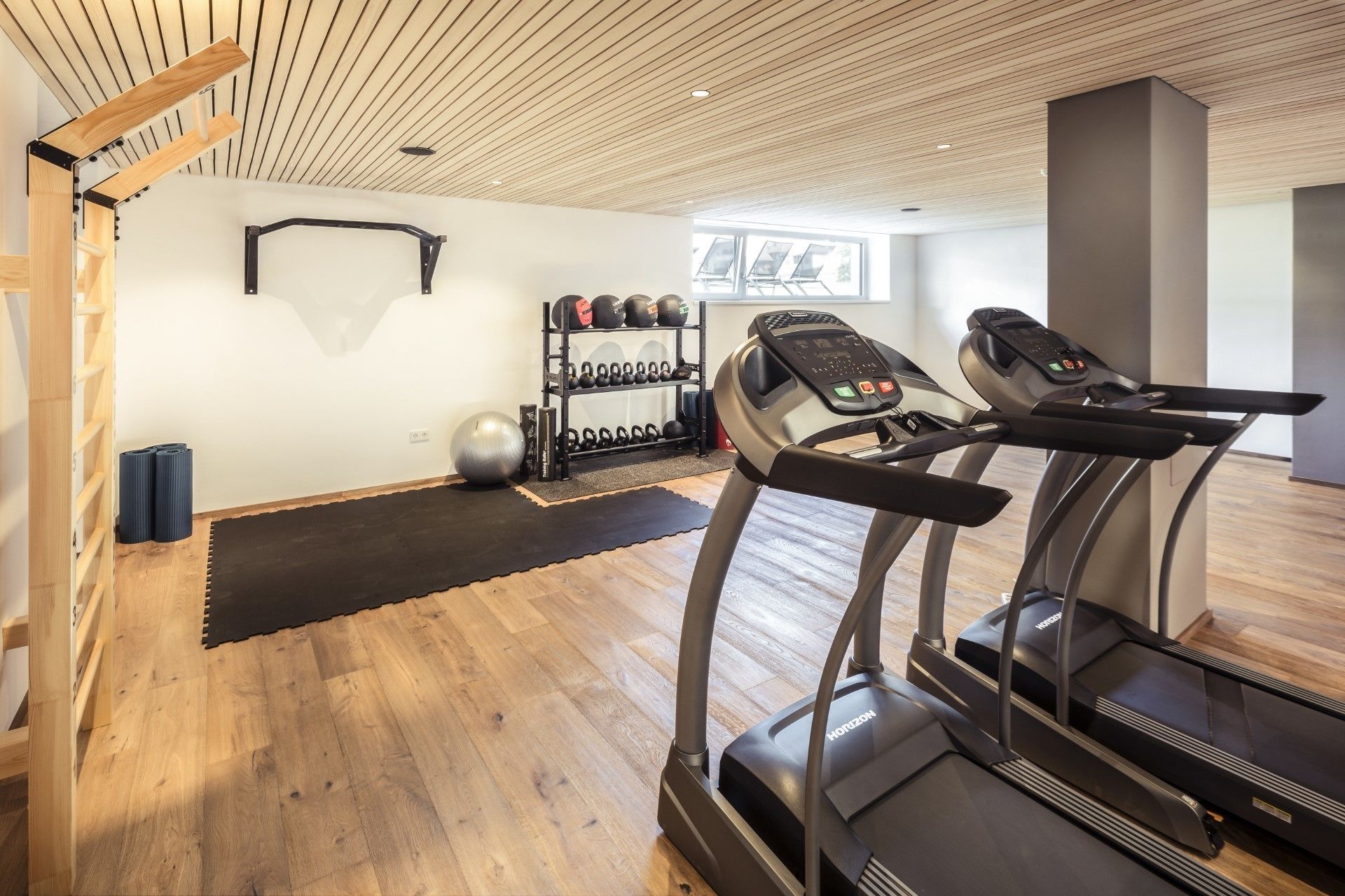 Una palestra con tapis roulant, rastrelliere per pesi e palle per esercizi.