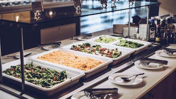 Un bufé con diversas opciones de comida, como ensaladas, cereales y un plato de carne.