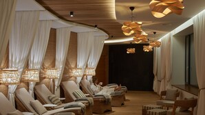 Een spa ruimte met comfortabele ligstoelen, een massagetafel en sfeerverlichting.