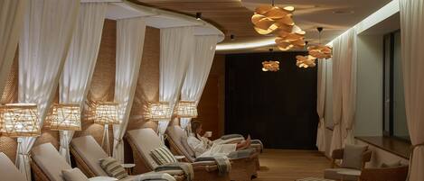 Un cuarto de spa con sillones reclinables, una camilla de masaje e iluminación ambiental.