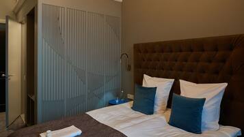 A hotel room with a large bed, a headboard, and a blue-striped wardrobe.