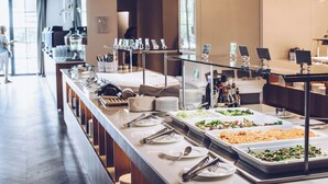 Een buffetopstelling met verschillende food stations, serveerbestek en een modern interieur.