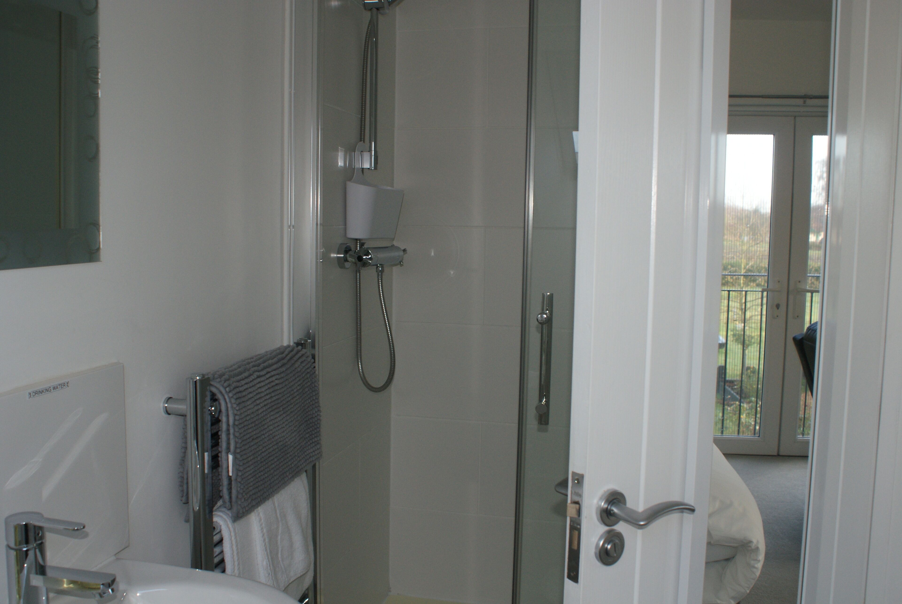A bathroom with a glass shower enclosure, a towel rack, and a toilet.