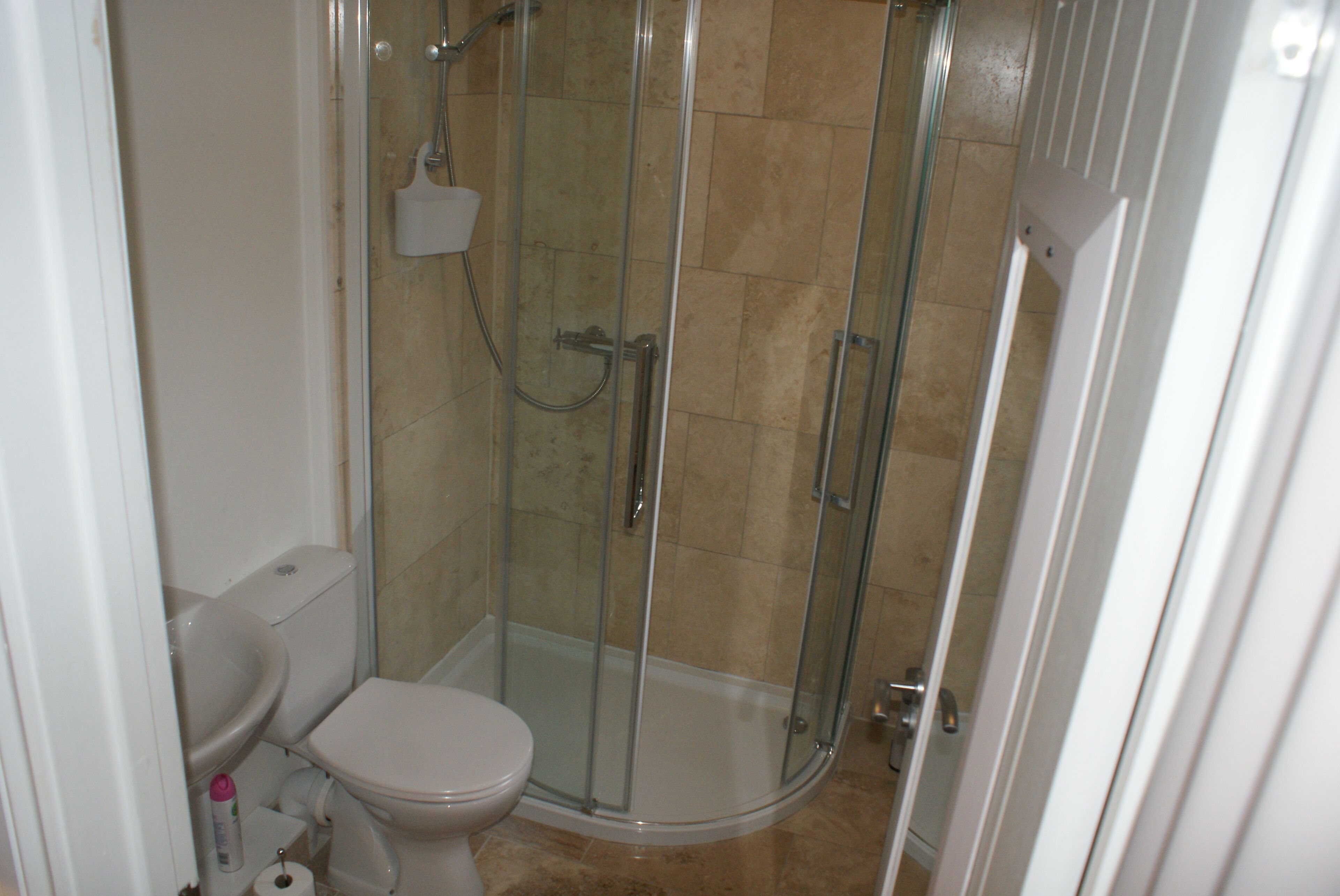 Een badkamer met een douchecabine, een toilet en een wastafel.