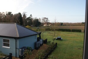 A house with a blue exterior, a fenced yard, and a small garden area with plants and a tree. - Tirah Bed and Breakfast (Leiston)