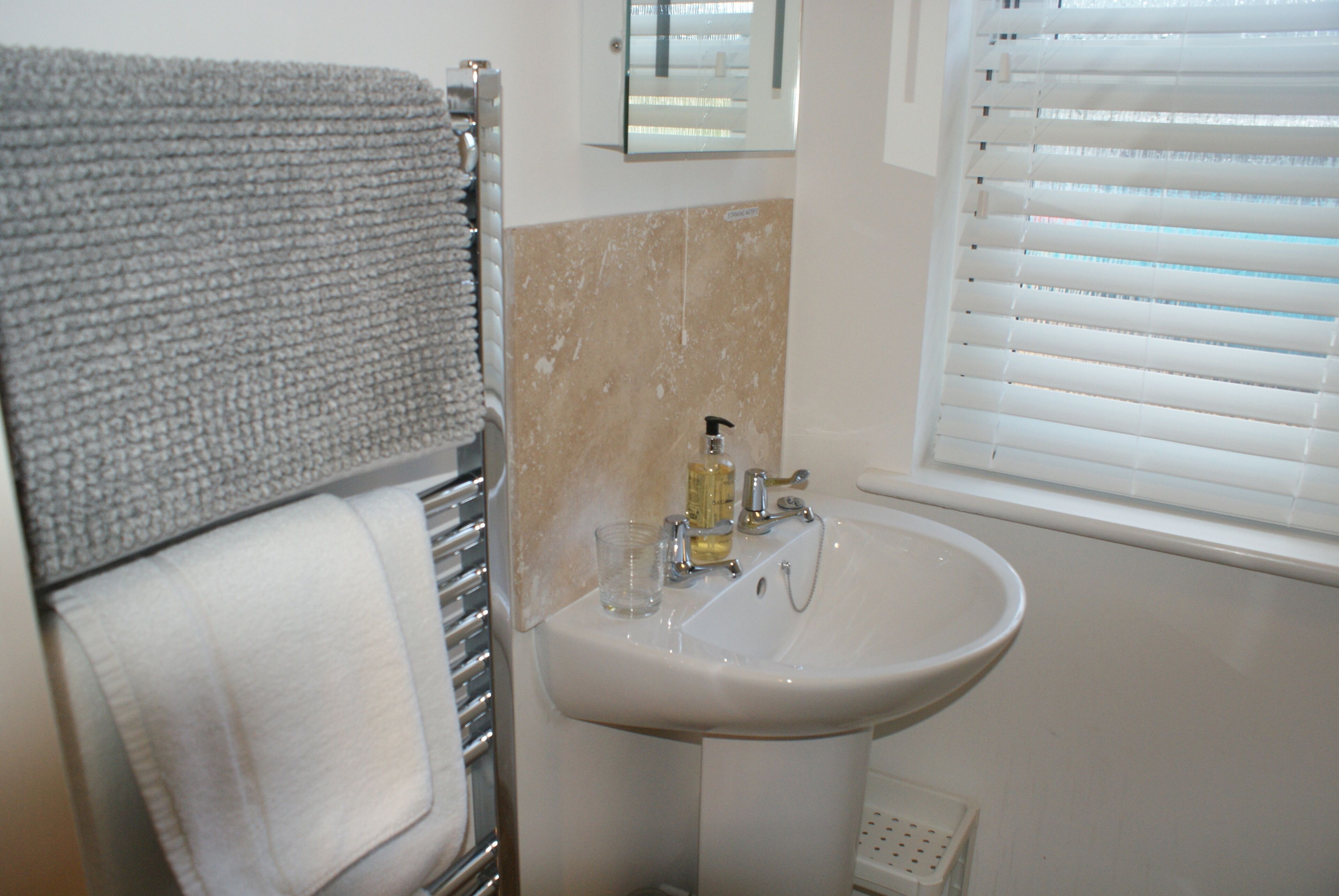 A bathroom with a white sink, a towel rack, and a mirror.