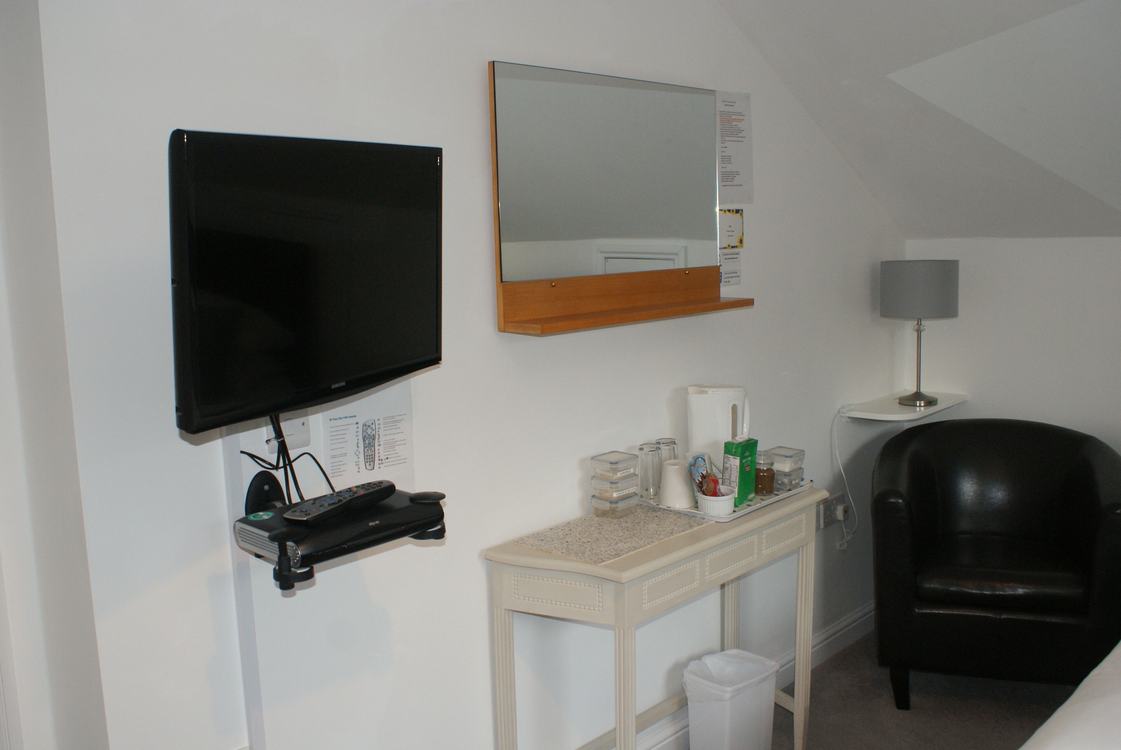 Une chambre d’hôtel équipée d’une télévision, d’un miroir, d’un bureau avec une lampe et d’une chaise.