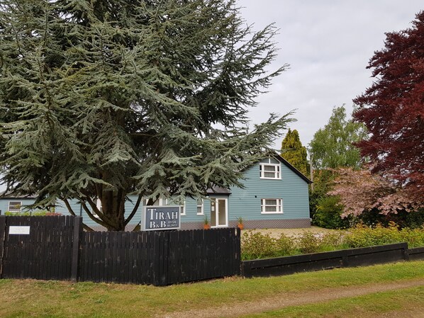 A two-story building with a sign for 'TIRAH B&B' and a large tree in front. - Tirah Bed and Breakfast (Leiston)