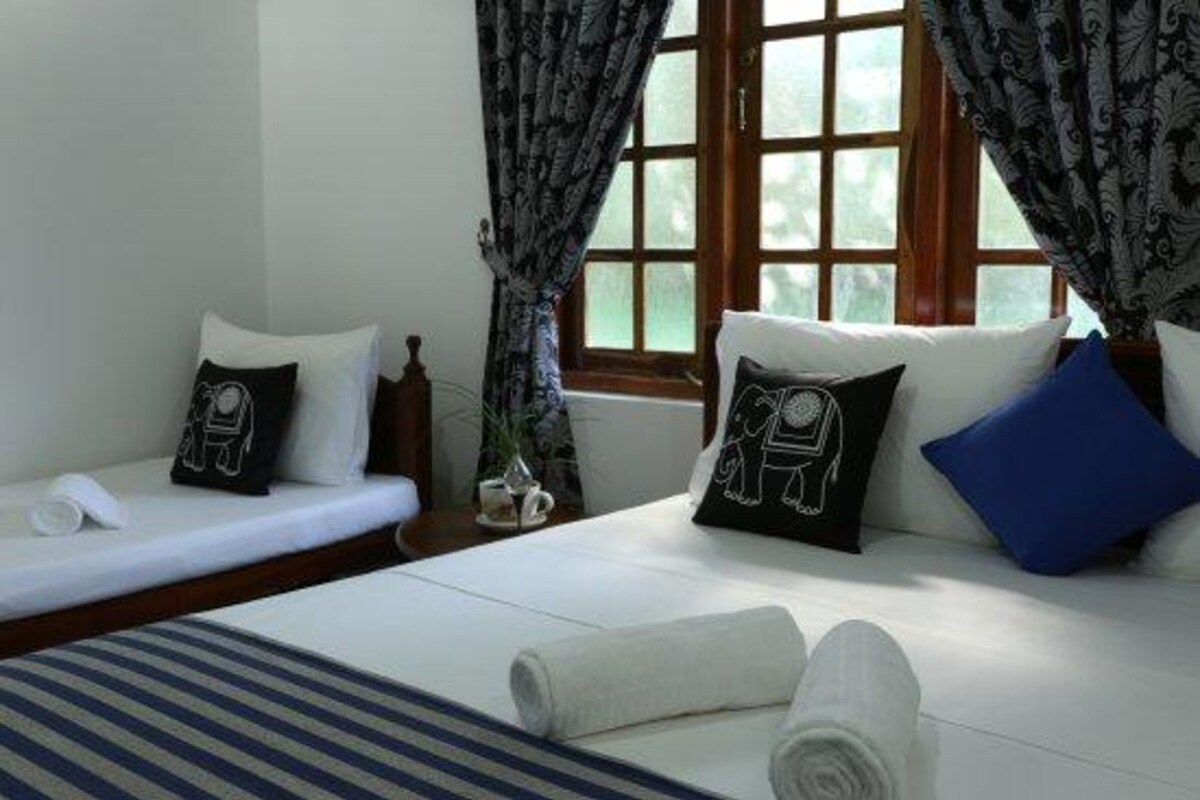 Habitación de hotel con dos camas, ropa de cama blanca y almohadas decorativas.