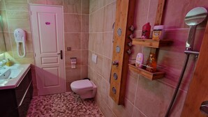 A bathroom with a sink, toilet, and shower area. There are toiletries on a shelf and a mirror above the sink. - Chez Stephanie (Chateauroux)