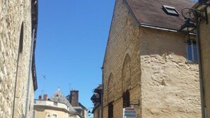 A narrow cobblestone street lined with historic stone buildings, featuring a sign for a local business. - Chez Stephanie (Chateauroux)