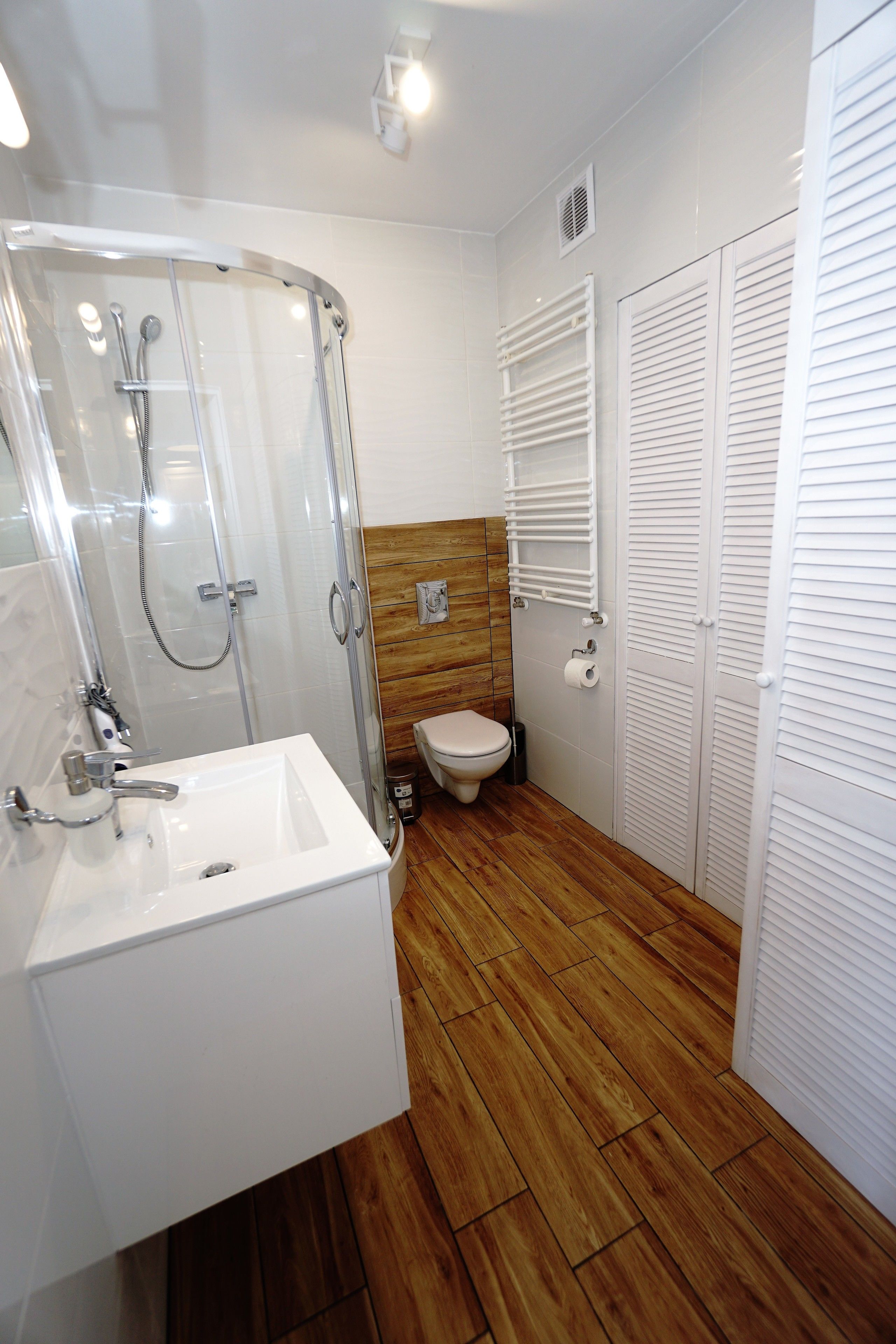 A bathroom with a glass-enclosed shower, a white sink, and a toilet.