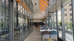 A modern dining area with glass walls, wooden flooring, and a high ceiling with orange accents. - ibis Styles Kunming Nanping Hotel (Kunming)