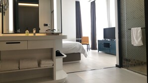 A modern hotel room with a large mirror, a bed, a TV, a desk, and a shower area. - ibis Styles Kunming Nanping Hotel (Kunming)