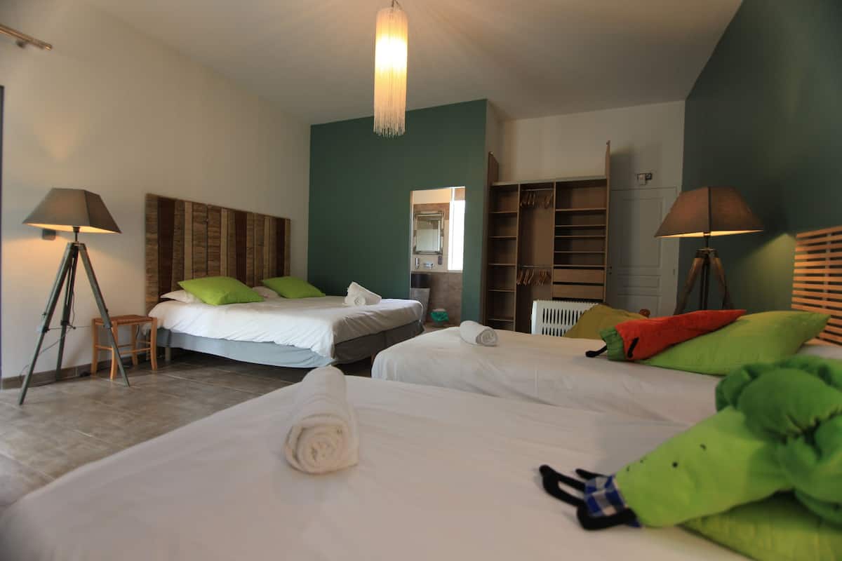 A hotel room with two beds, a wardrobe, and a bathroom.