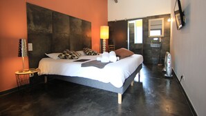 Quarto moderno com uma cama grande, mesa de cabeceira, abajur e espelho na parede.