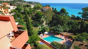 Un quartier résidentiel doté d’une piscine, entouré de verdure et offrant une vue sur la côte.