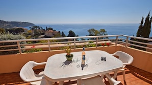 Une terrasse avec une table et des chaises, une bouteille et des verres à vin.