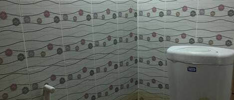 Un baño pequeño con inodoro, ducha y pared con estampado floral.