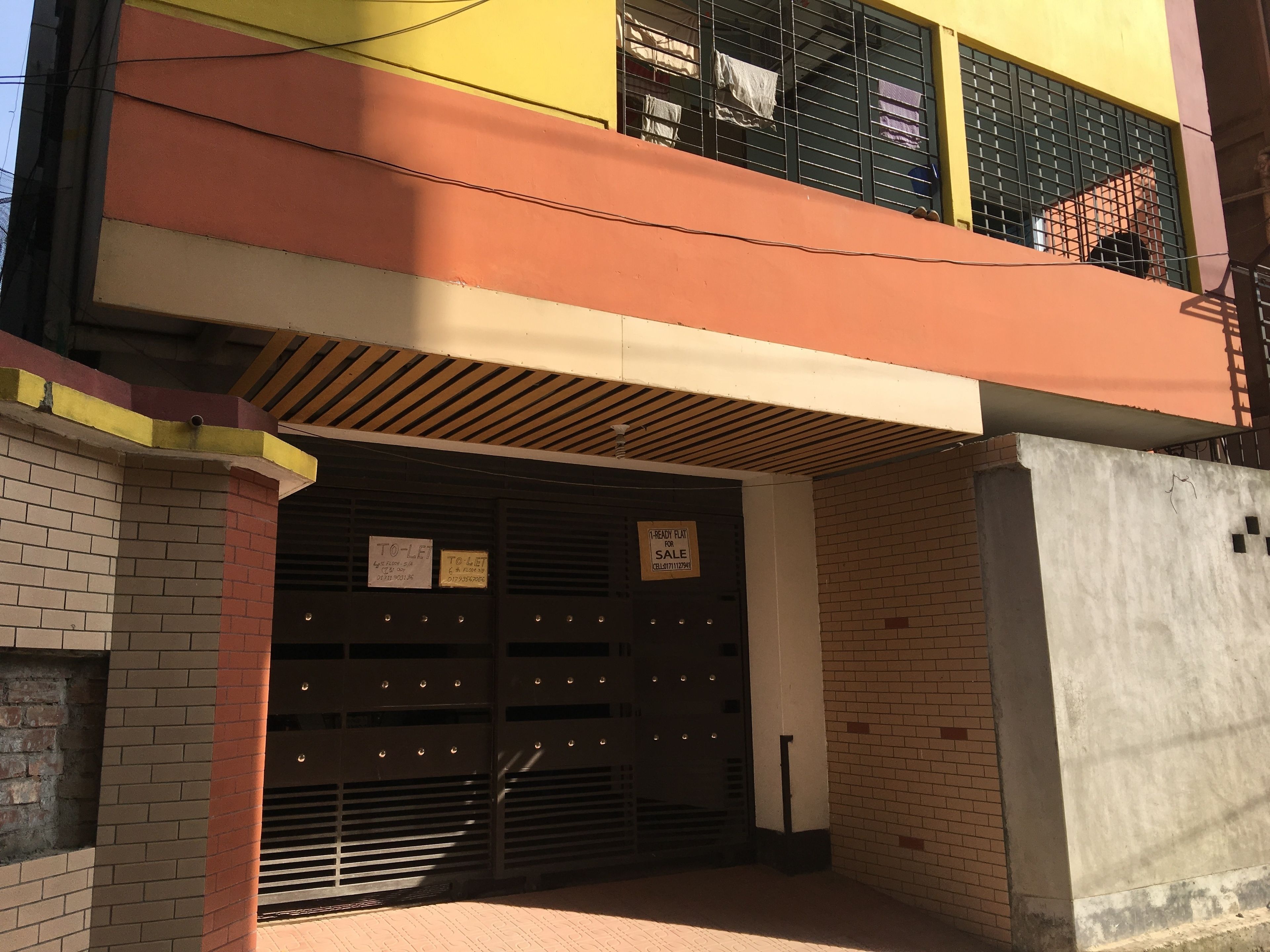 A multi-story building with a garage entrance, a balcony, and a 'TO-LET' sign.