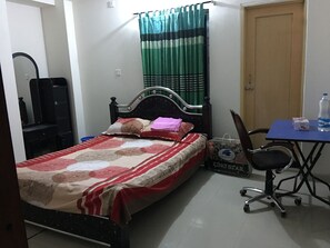 A bedroom with a bed, a desk, a chair, a mirror, and a curtain. - AMtec Fazilla Castle (Dhaka)