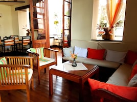 Una sala de estar acogedora con muebles de madera, un sofá con cojines rojos y blancos, y una mesa con un florero.