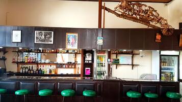 A bar with wooden bar stools and shelves stocked with bottles.
