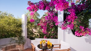 A patio with a round table and chairs, surrounded by white walls and vibrant bougainvillea flowers. - Orionas Village (Chania)